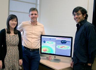Heather Fong, Harald Pfeiffer and Prayush Kumar stand around a computer.