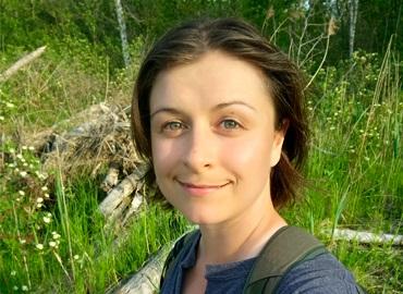 Headshot of Malia Robinson in a green field of grasses and wildflowers