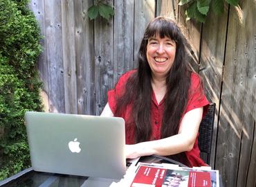 Margaret Fulford in her backyard working on a laptop.