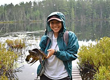A woman standing in a marsh holding a turtle