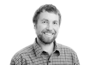 black and white headshot of Martin Krkosek - he is smiling warmly and is bearded