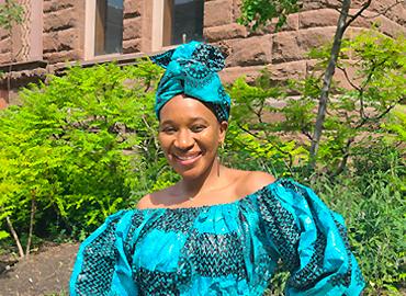 Matida Daffeh in a colourful dress and headwrap on U of T campus