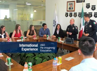 students sitting around a table listening to two Mexican officials