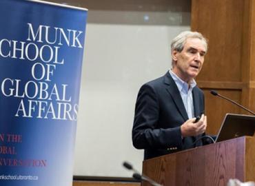 Michael Ignatieff speaking at a podium in front of a banner for the Munk School of Global Affairs