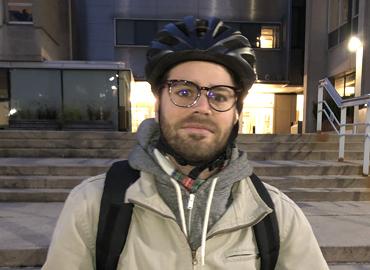 Mischa Young poses wearing a bike helmet.