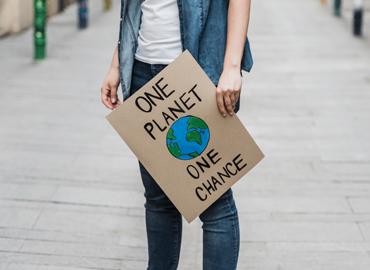 An activist holding banner with words one planet, one chance