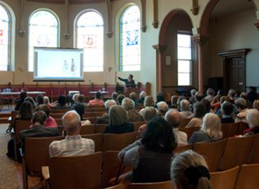 Audience members watch a presentation during the recent symposium discussing Eugene Onegin.