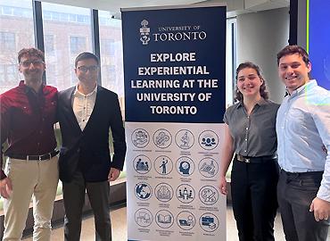 Four people standing beside a sign that says, Explore Experiential Learning at the University of Toronto.
