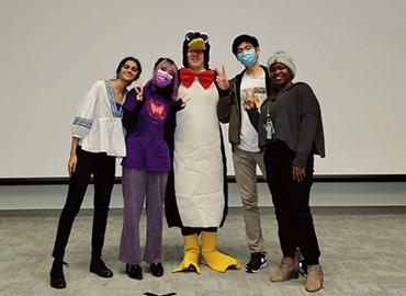 Donald Ainslie in a penguin costume with some of his students from PHL100Y