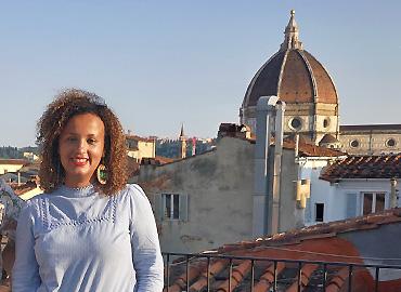 Angelica Pesarini standing on a rooftop in Florence, the Cathedral of Santa Maria del Fiore in background   