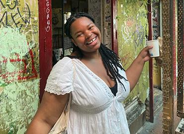 Aïsha Philippe  smiling warmly in front of a painted mural wall