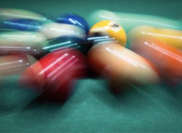 Pool balls rolling quickly across a table.