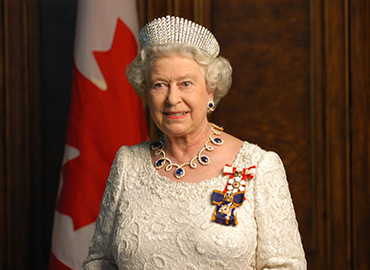 Queen Elizabeth II in front of a Canadian flag wearing royal finery