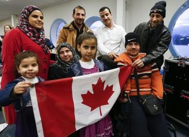 A Syrian refugee family at a welcoming dinner holding a Canadian flag