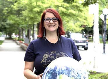 Renée Hložek holding a model universe globe outdoors