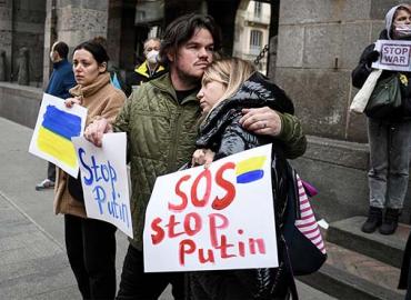 A couple hugging in a protest - holding a sign saying SOS Stop Putin