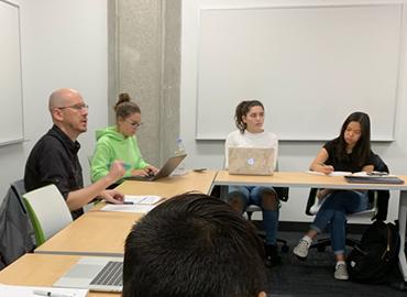 Professor Nathan Sanders and students sit around a u-shape of tables during LIN 197 class