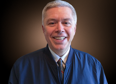 Man looking at camera smiling. He&amp;#039;s wearing a blue jacket.