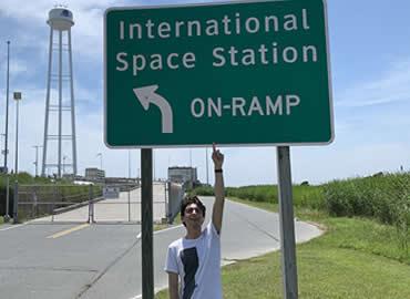 Student pointing up at NASA street sign