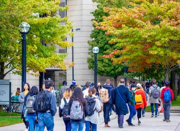 A group of students walking outside on a fall day at the St. George downtown campus.