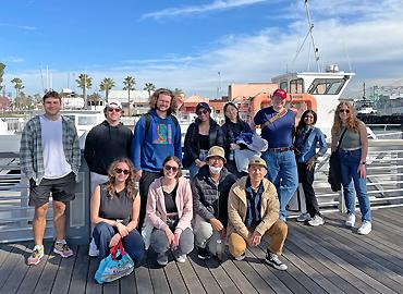 A group of students standing on a dock.