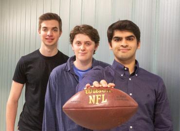 three male students one holding a football