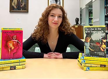 Tamara Doiny sitting beside multiple Nancy Drew books.