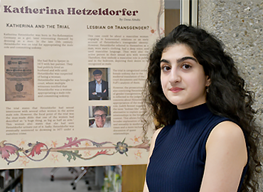 A student standing in front of her research poster