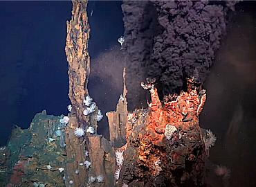 A hydrothermal vent underwater that looks like a small underwater volcano erupting.