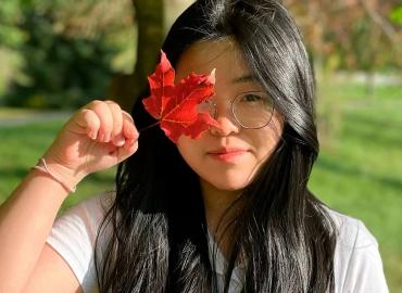 Ngọc Anh Thư (Tina) Huỳnh holding a red maple leaf.