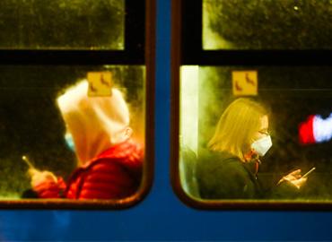 two people wearing masks on a train
