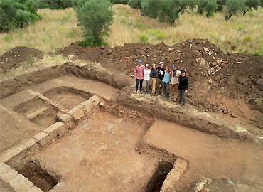 A research team standing beside a trench in the soil