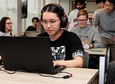 Students test out video games on laptops in a classroom  