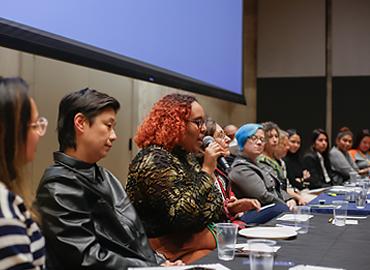 A group of people speaking on a panel at a large table.