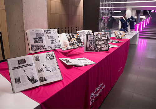A long table of open books and images showing the history of Rotman Commerce.