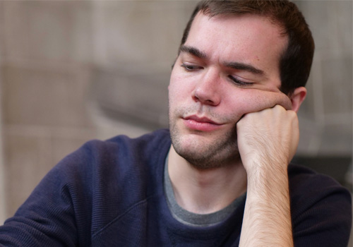 A person sitting, leaning with their head on their hand.