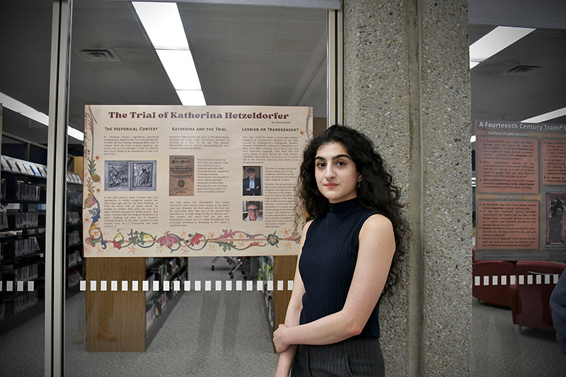 A student standing in front of a research poster