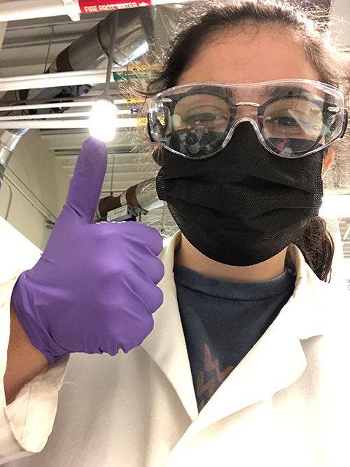 Patricia Stewart wearing googles and gloves and a mask giving a thumbs up.