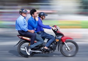 Three people on a scooter