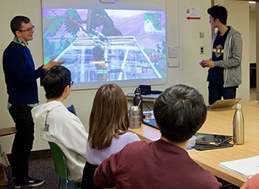 Assistant Professor Felan Parker shows off a new video game in front of an engaged class.