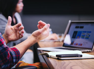 Two hands facing palms up in front of a computer.