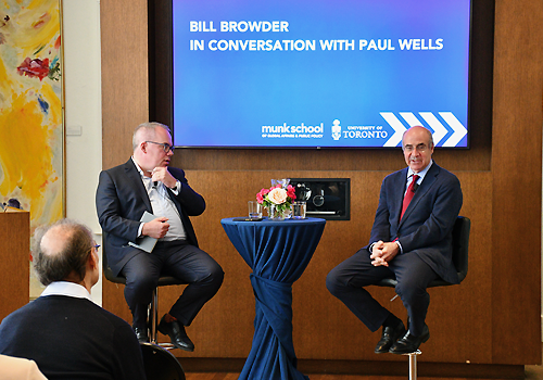 Bill Browder and Paul Wells speaking to an audience on a stage.