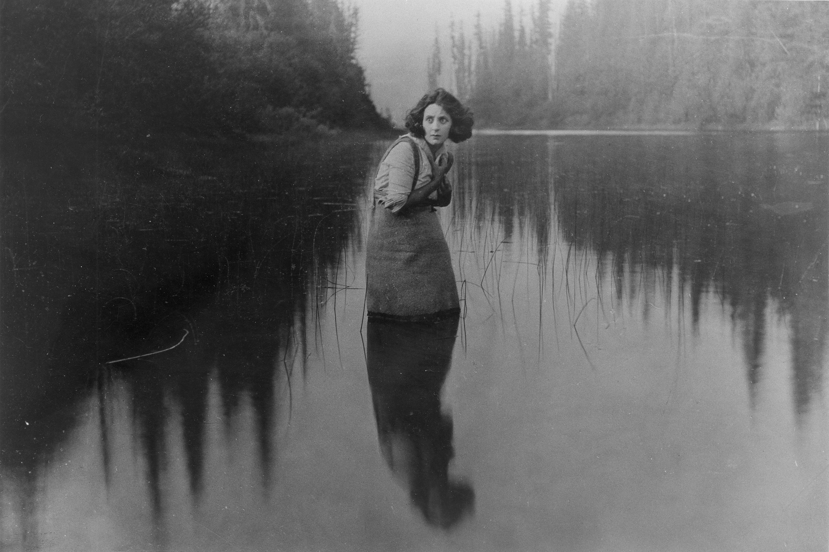 Nell Shipman standing in a shallow lake in a forrest