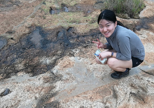 Xuefei Fan standing beside puddles and rocks.